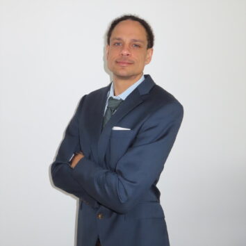 A professional headshot of John Bates, an attorney, smiling slightly and posing with his arms crossed.